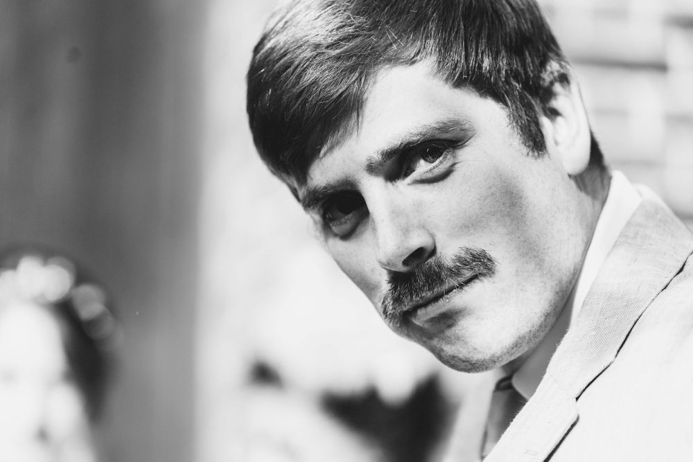 Black and white portrait of a man with a thick mustache wearing a light colored suit.