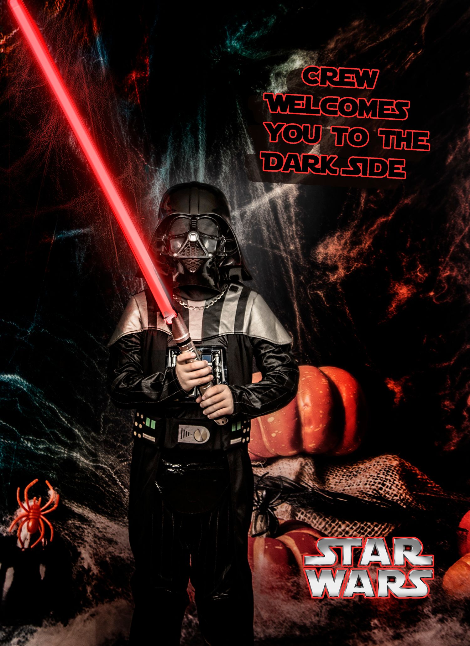 A child dressed as Darth Vader poses with a red lightsaber against a dark Halloween backdrop.