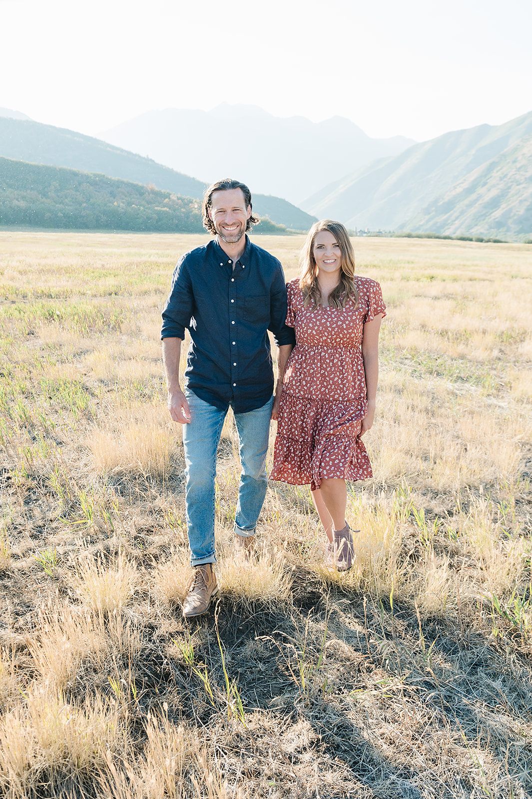 Outdoor portrait in a mountain meadow with golden grasses and peaks in the distance.