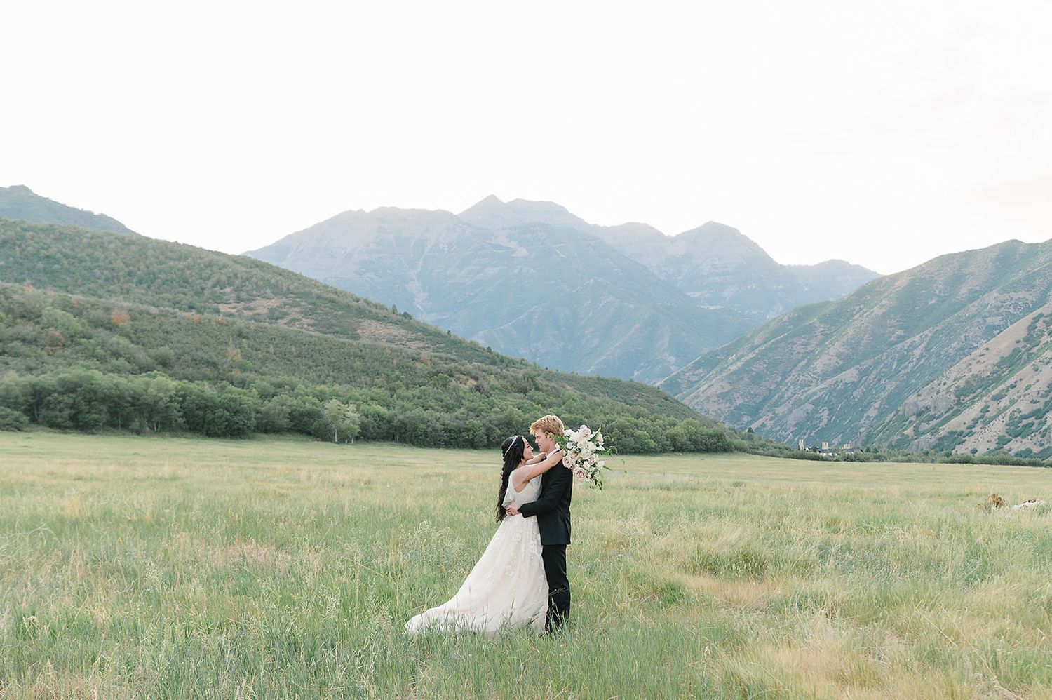 Wedding couple dancing in a scenic mountain meadow surrounded by majestic peaks.