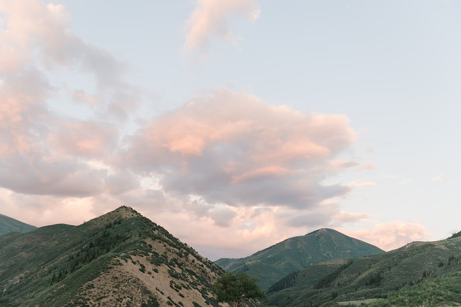 Dramatic mountain landscape at sunset with pink clouds and rugged peaks.