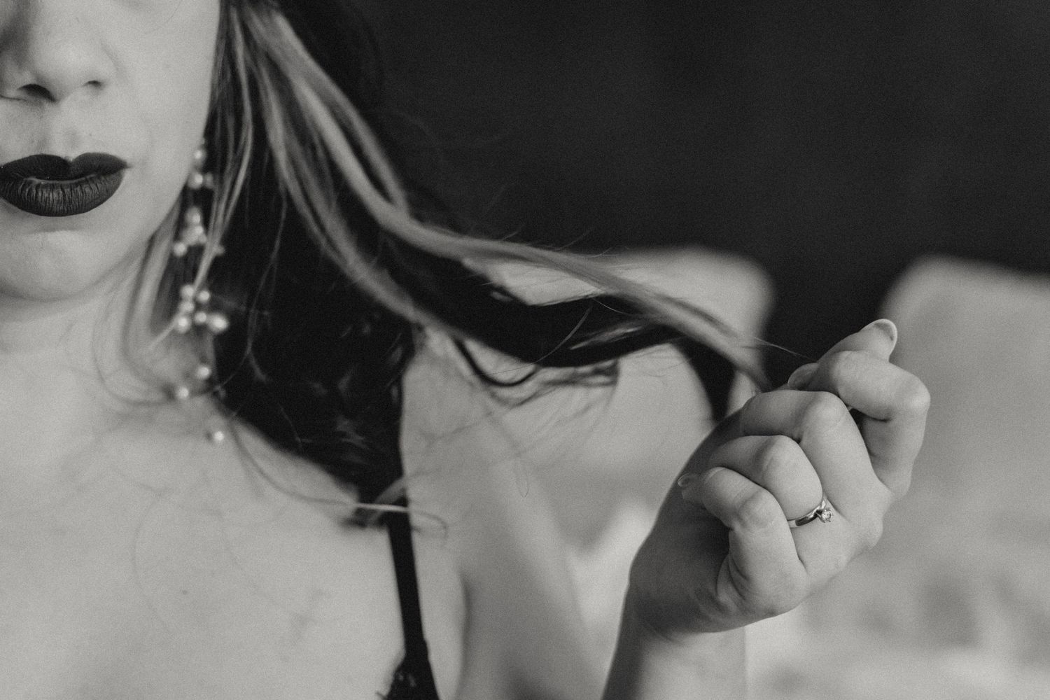 Artistic black and white portrait showing jewelry and dark lipstick.