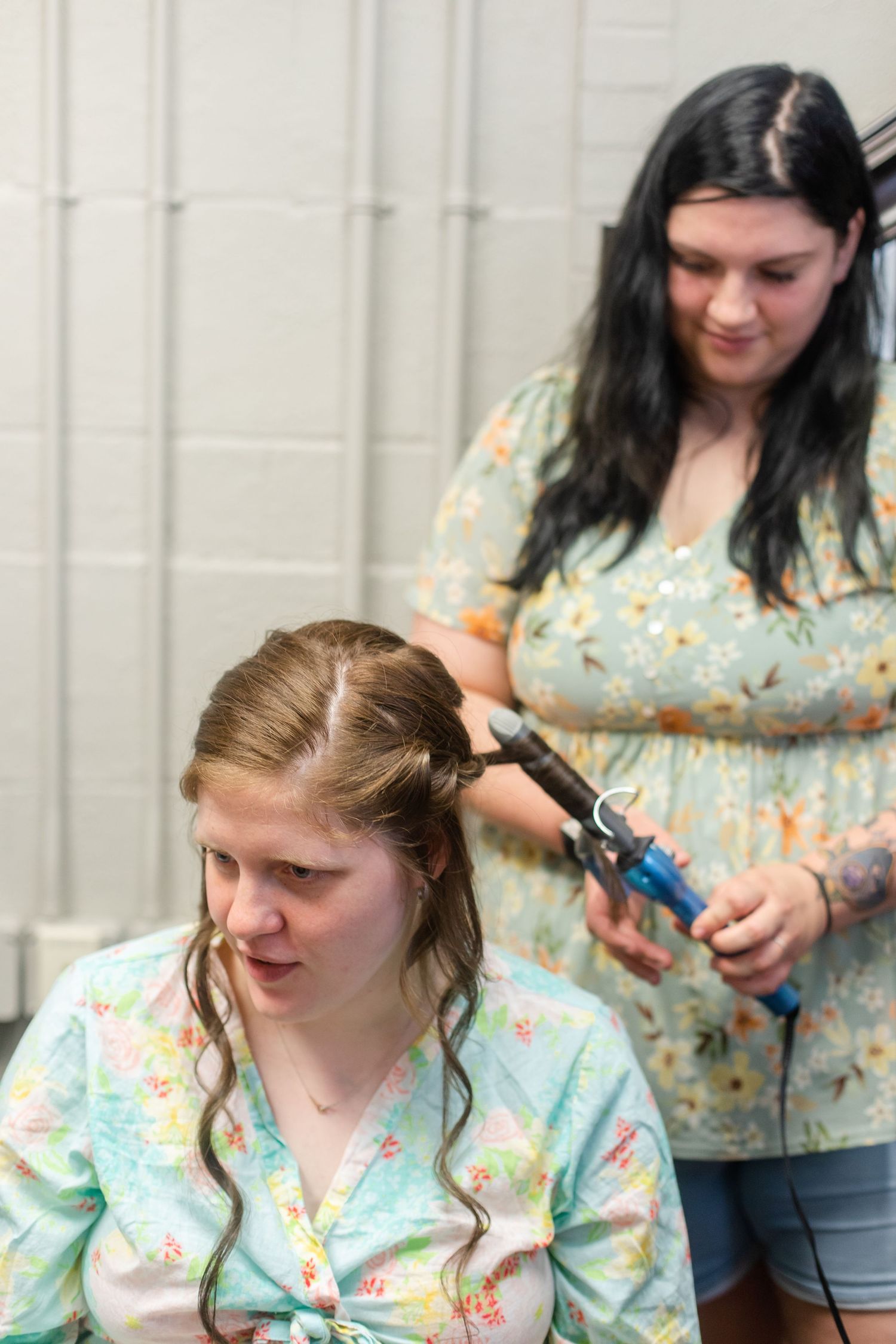Hair styling session with floral print robes during wedding preparations.