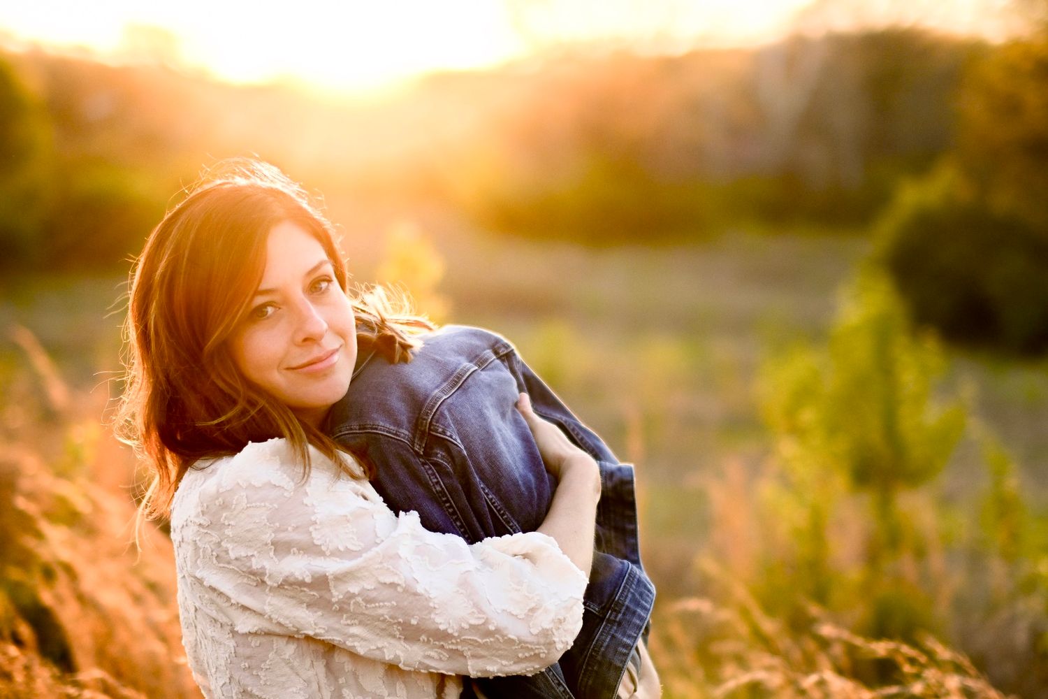 Portrait at sunset in field with golden light and natural backdrop.
