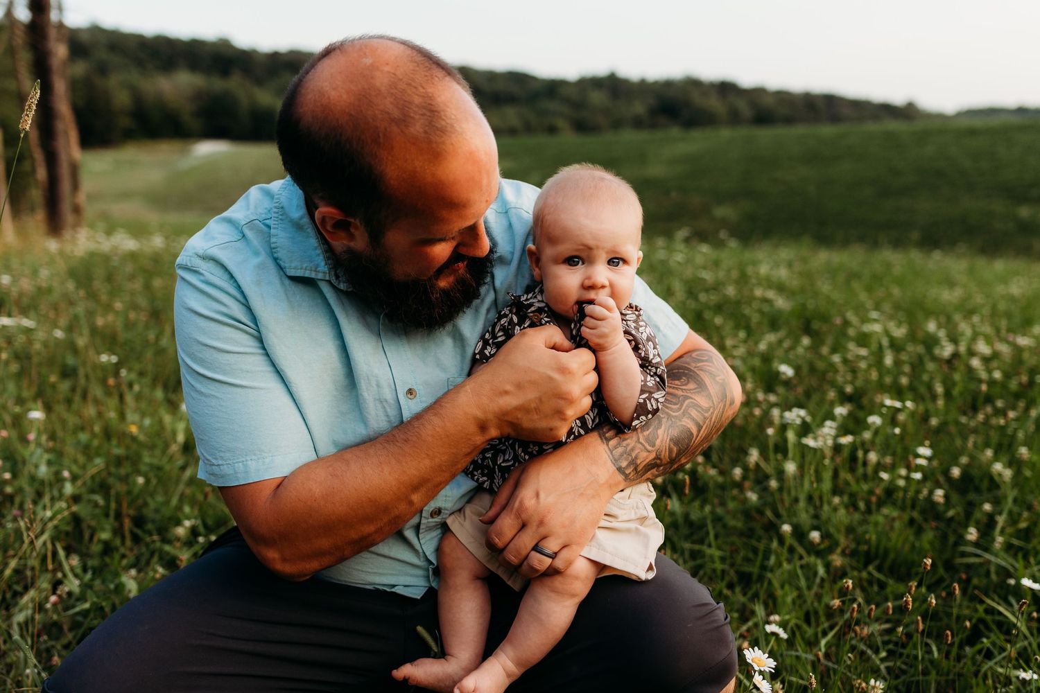 An intimate family moment captured in a sunny meadow with wildflowers.