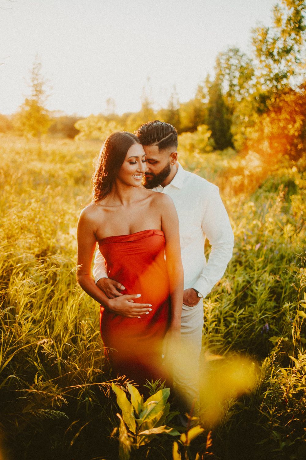 Intimate couples portrait in a golden sunlit field during sunset.