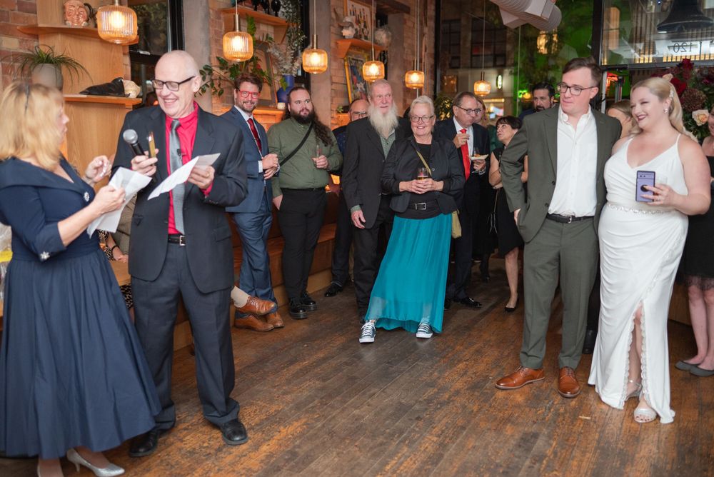 Wedding reception gathering with guests mingling in warmly lit indoor venue.