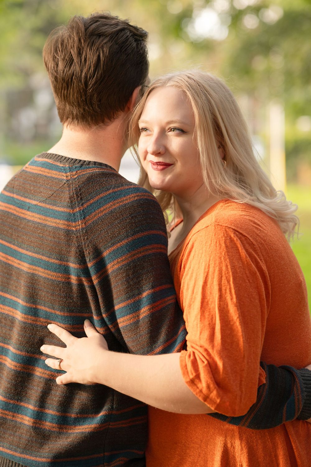An intimate moment shared between two people in a park setting with warm lighting.