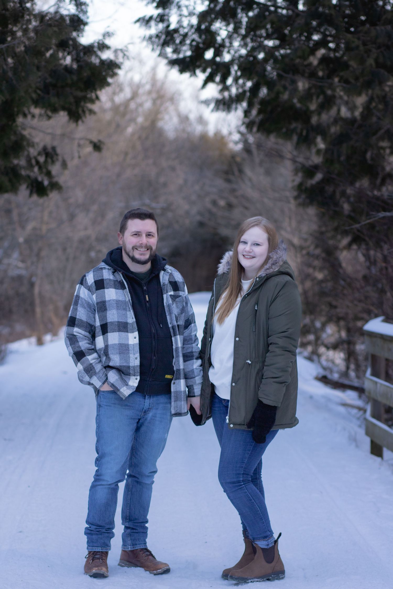 Winter portrait on snowy path framed by evergreen trees.
