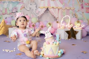 Whimsical circus-themed party setup with pastel decorations, balloons, and tulle in soft pink and purple tones.