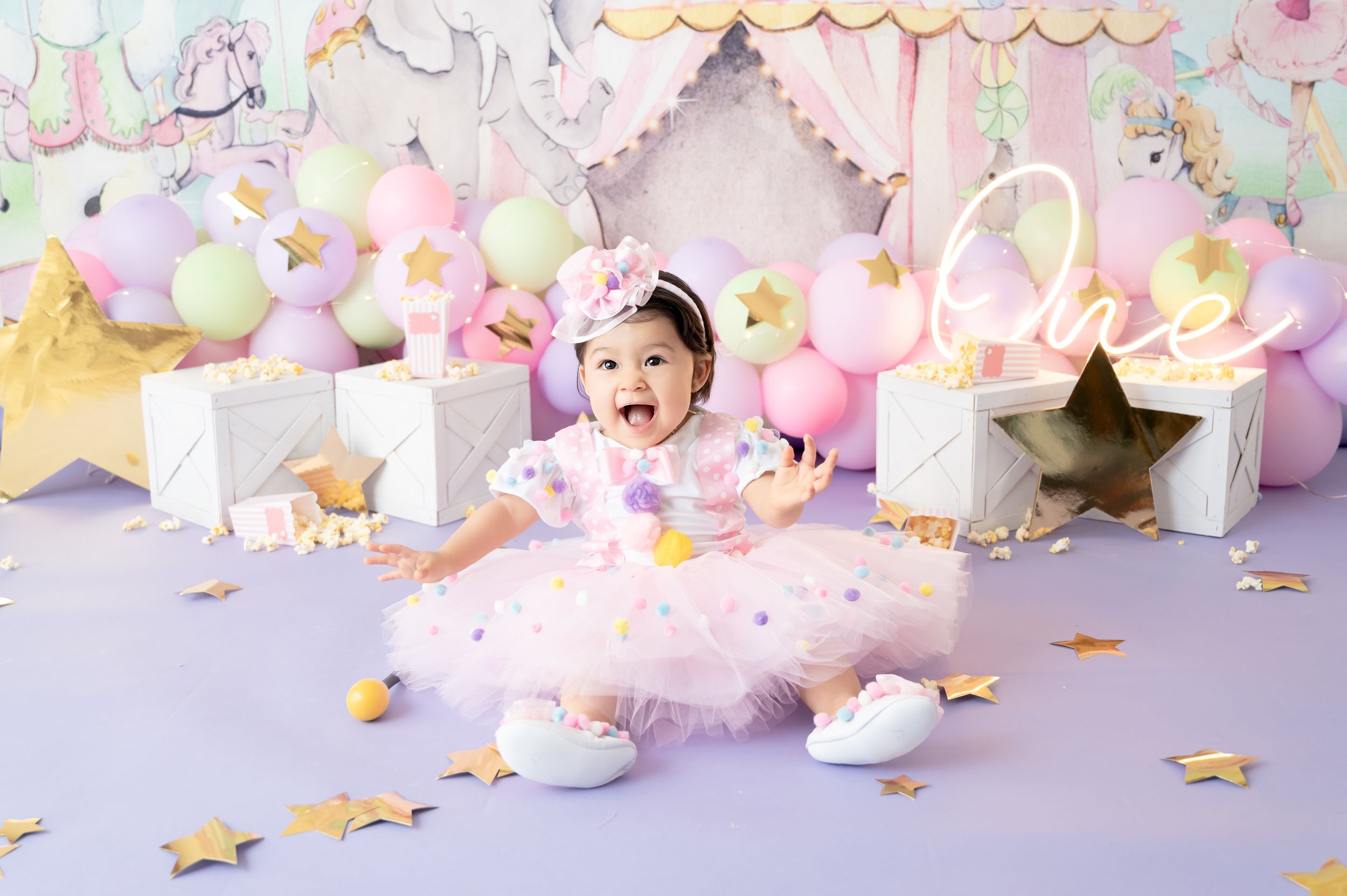 Dreamy circus party backdrop with pink tulle, gold stars, and pastel balloon arrangements.