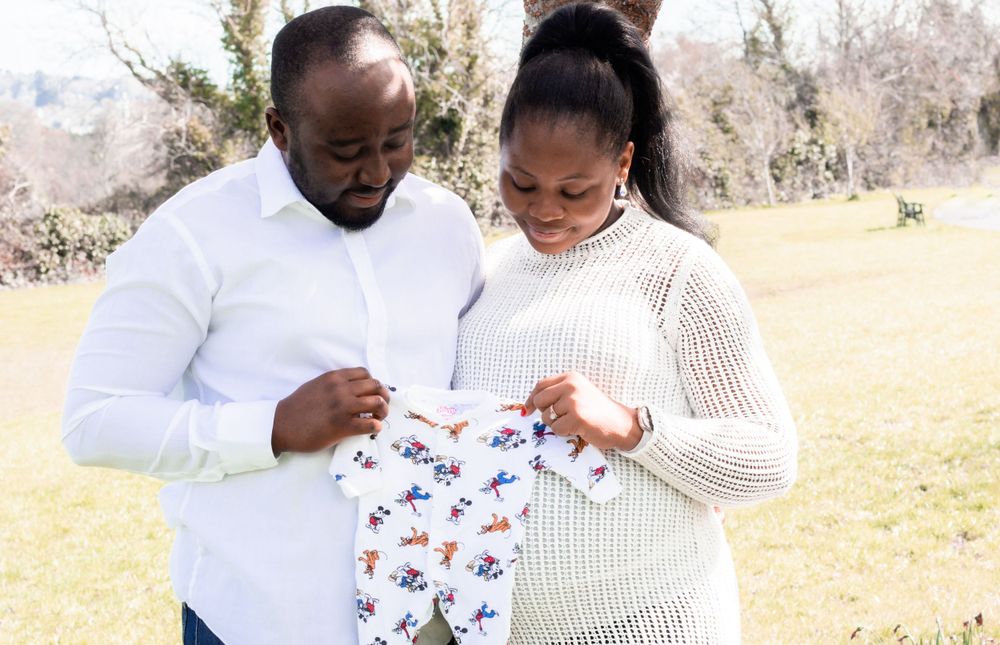A couple holds a baby onesie