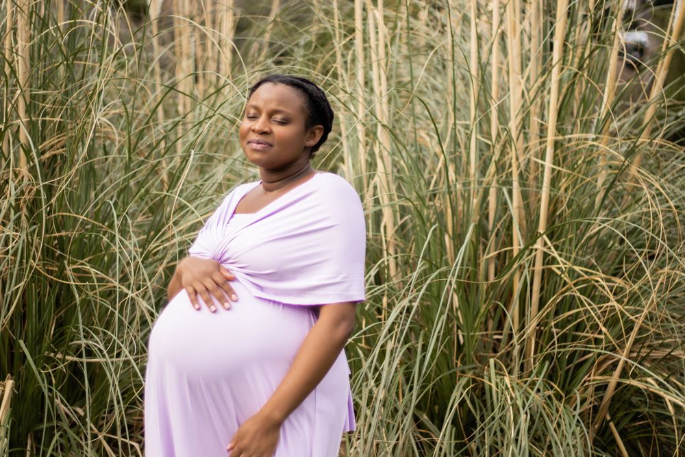 Person in lavender dress standing among tall reeds in nature setting.