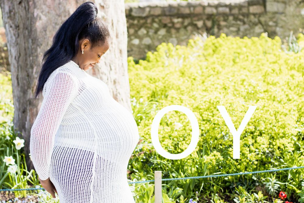 Pregnancy portrait with 'BOY' text overlay in sunny garden setting.