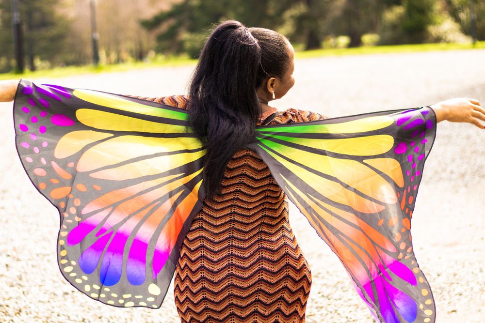 Person wearing colorful butterfly wings spreading joy outdoors.