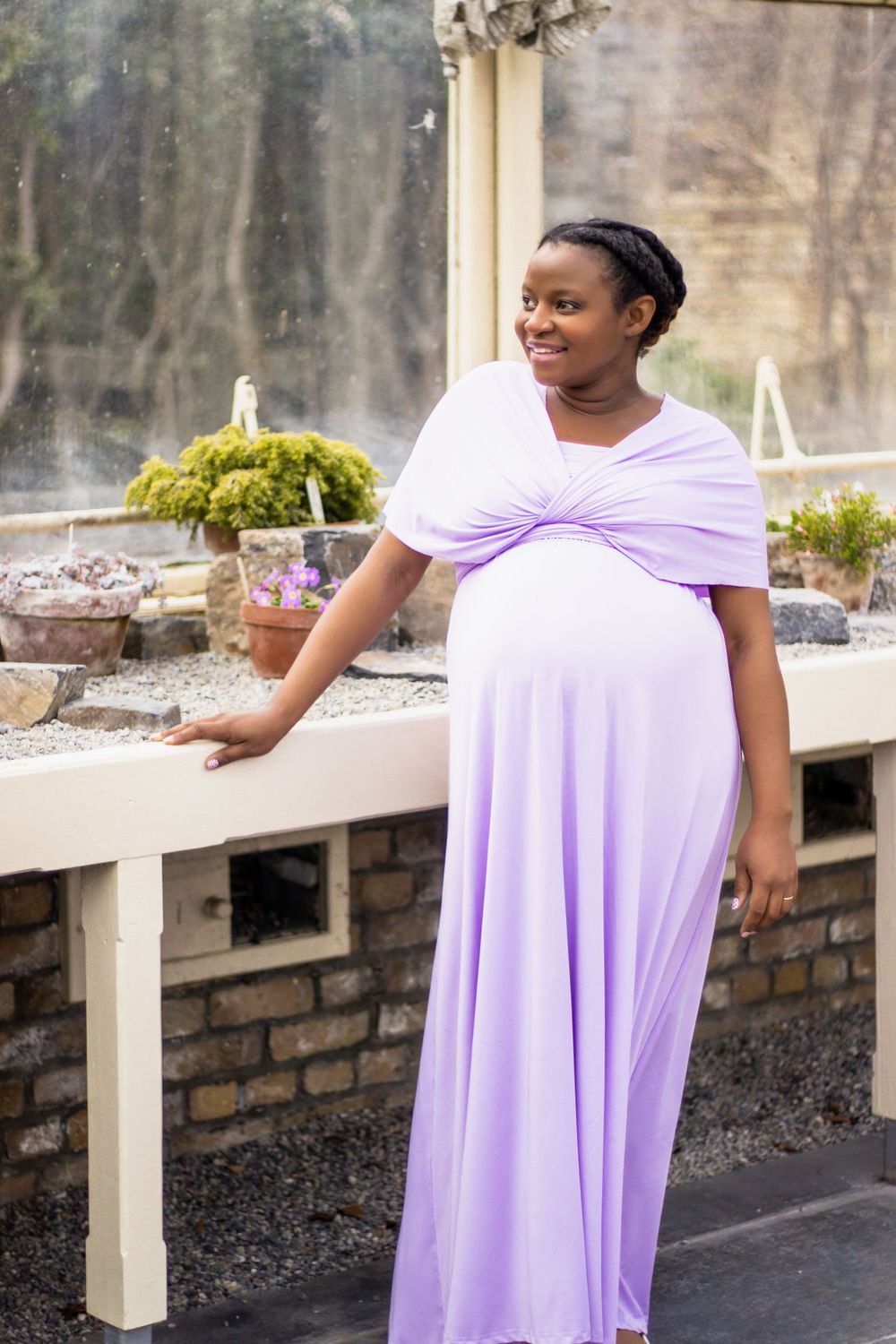 Purple maternity gown photographed in outdoor garden setting.