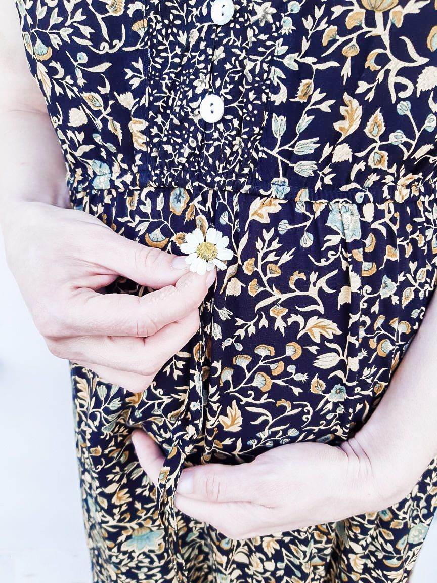 Hands gently holding floral fabric with delicate navy and gold patterns.