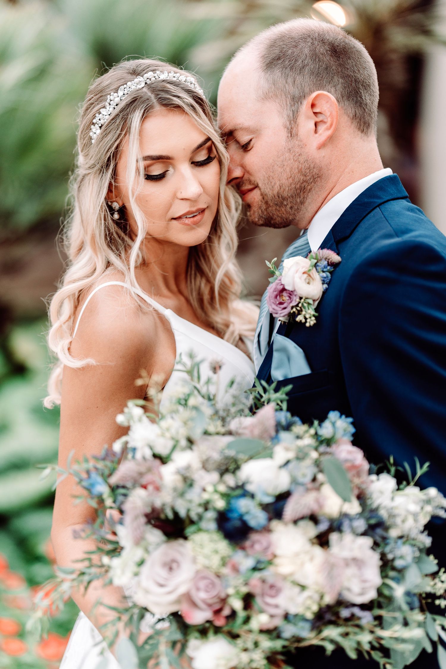 An intimate wedding portrait featuring a beautiful bouquet of pastel flowers and greenery.