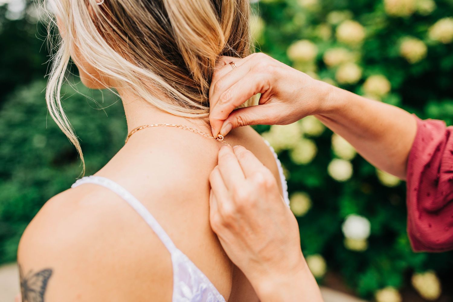 Close-up of hands fastening a necklace clasp with soft natural lighting.
