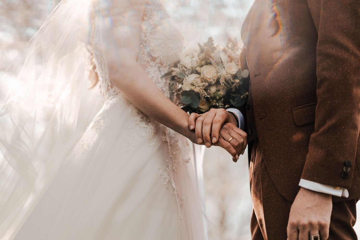 Intimate wedding ceremony outdoors with couple holding hands in warm sunlight.