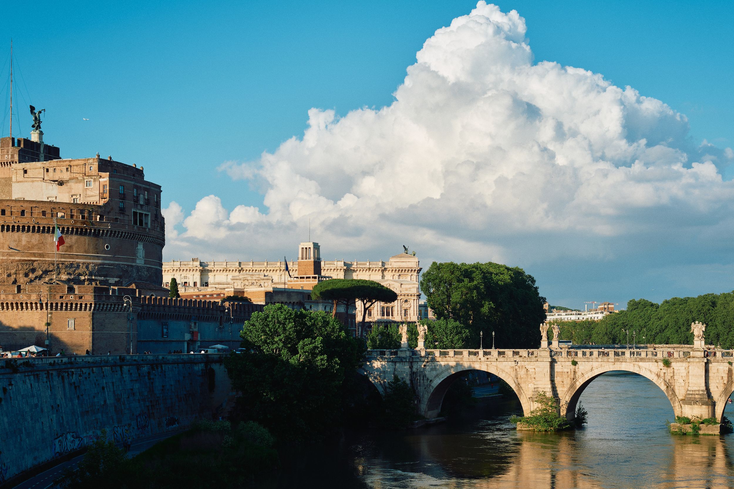 Castel Sant'Angelo and bridge over Tiber River in Rome against cloudy sky.