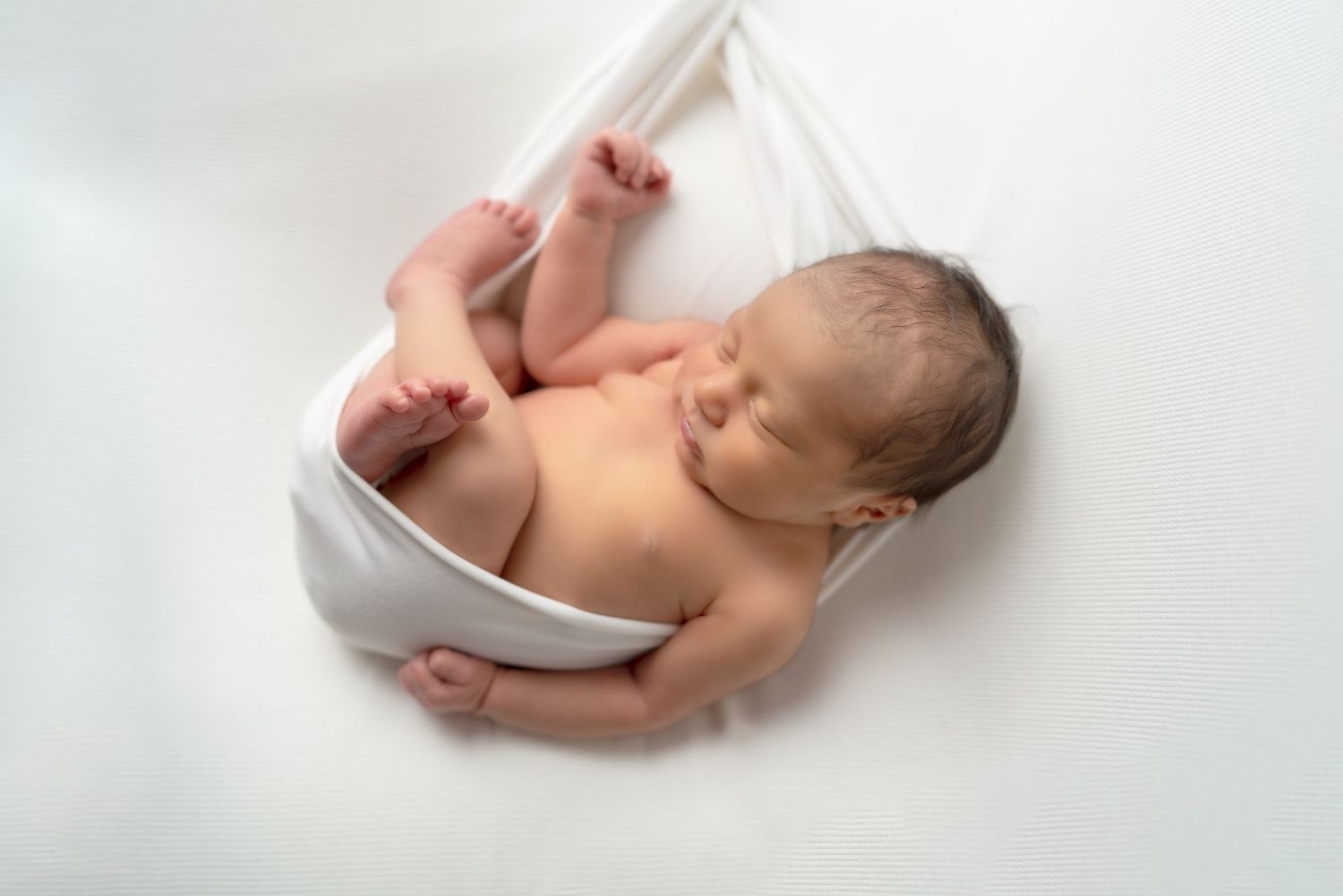 Minimalist newborn photography on white background with soft natural lighting.