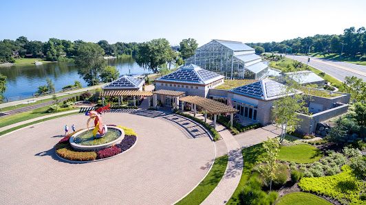 Aerial view of a lakeside pavilion with circular plaza and landscaped grounds.
