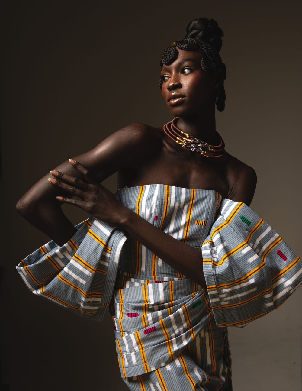 Fashion model poses in a striking striped off-shoulder top with ruffled details against dark background.