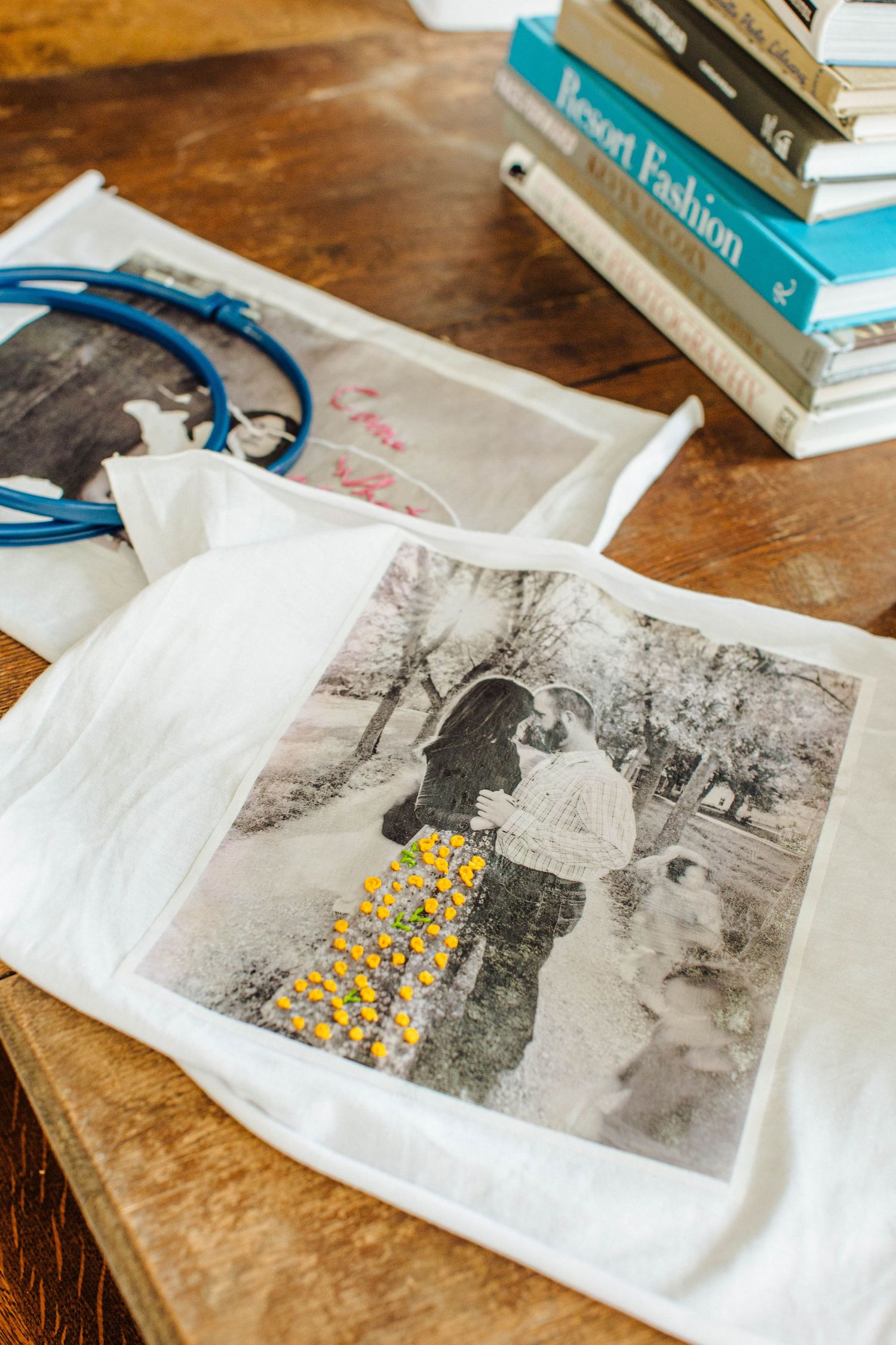 Black and white photographs being embroidered with yellow thread details on white fabric.
