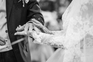 Black and white photo capturing the intimate moment of wedding ring exchange.