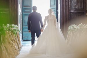 Silhouetted couple walking through church doorway with flowing white wedding dress.
