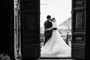 Black and white silhouette of newlyweds framed by grand church doorway.