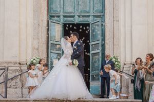 Joyful wedding celebration with confetti outside historic church entrance.