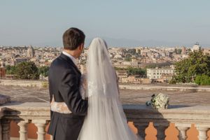 A romantic wedding photoshoot overlooking the cityscape of Rome at sunset.