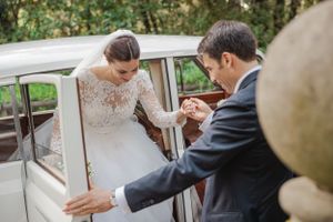 A tender moment between newlyweds next to a vintage white wedding car.