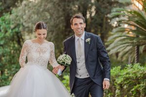 Newlyweds share joyful moments walking through a lush garden pathway.