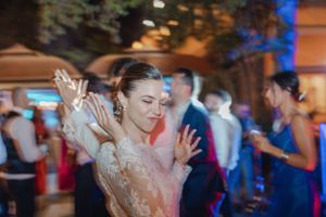 Wedding reception dance party with guests celebrating under colorful lighting.