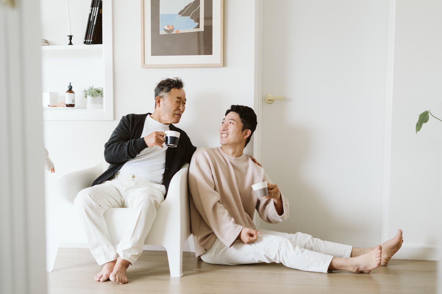 Father and son. Holding coffee and looking at each other.