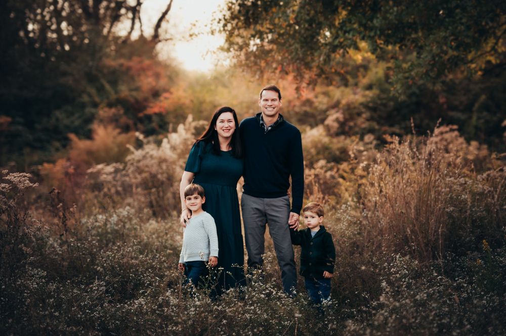 Family of 4 stand in a field of fall flowers as the sun sets behind them for Chattanooga fall mini session