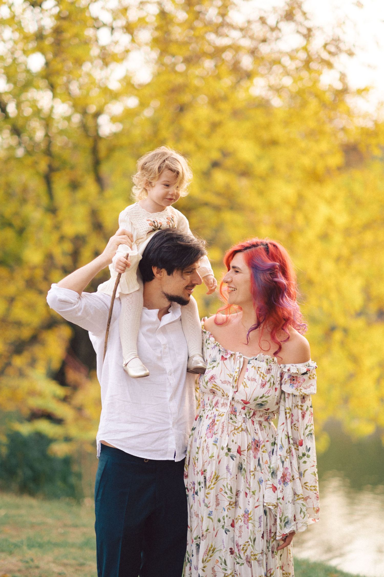 A family enjoying a tender moment in golden autumn light by the water.