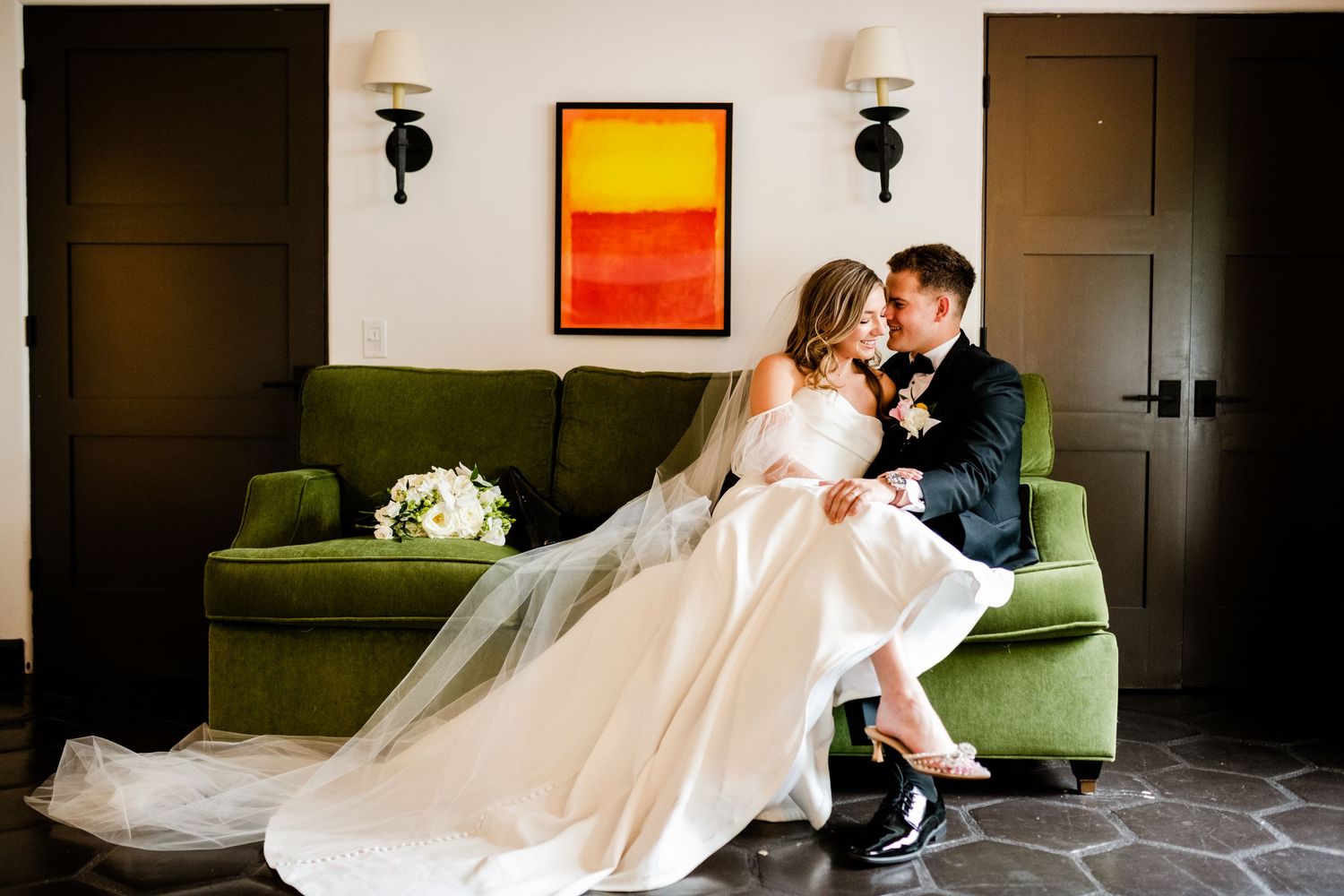 A elegant wedding scene on a green velvet couch with modern interior decor.