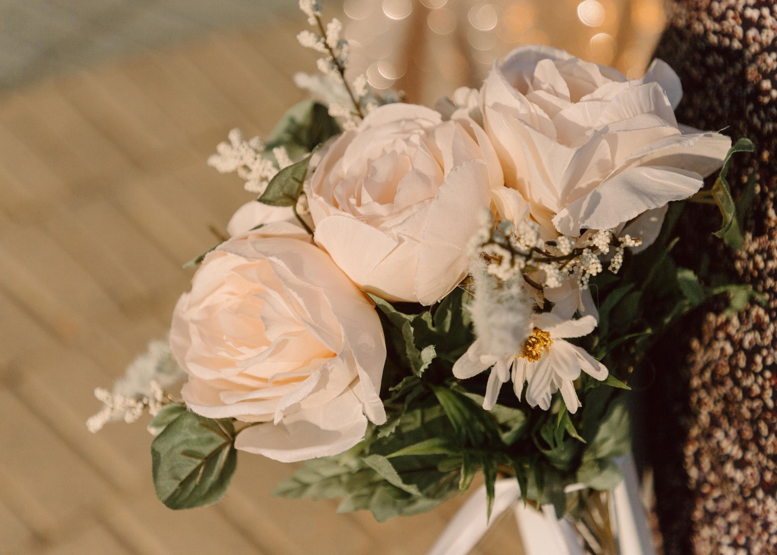 Elegant arrangement of peach roses and daisies with delicate baby's breath in soft focus.