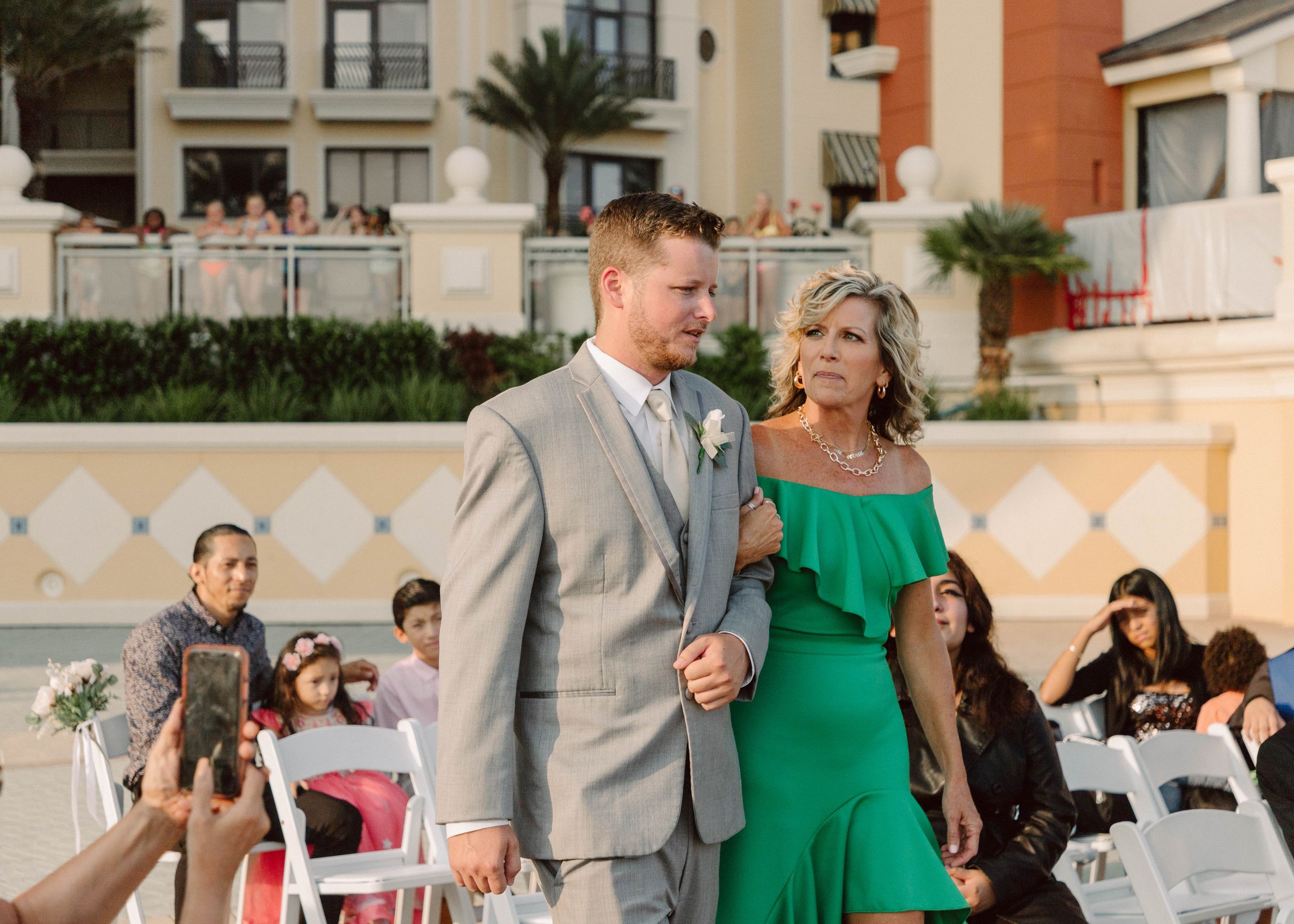 Wedding ceremony entrance on a beachfront patio with chairs and decorative architecture.