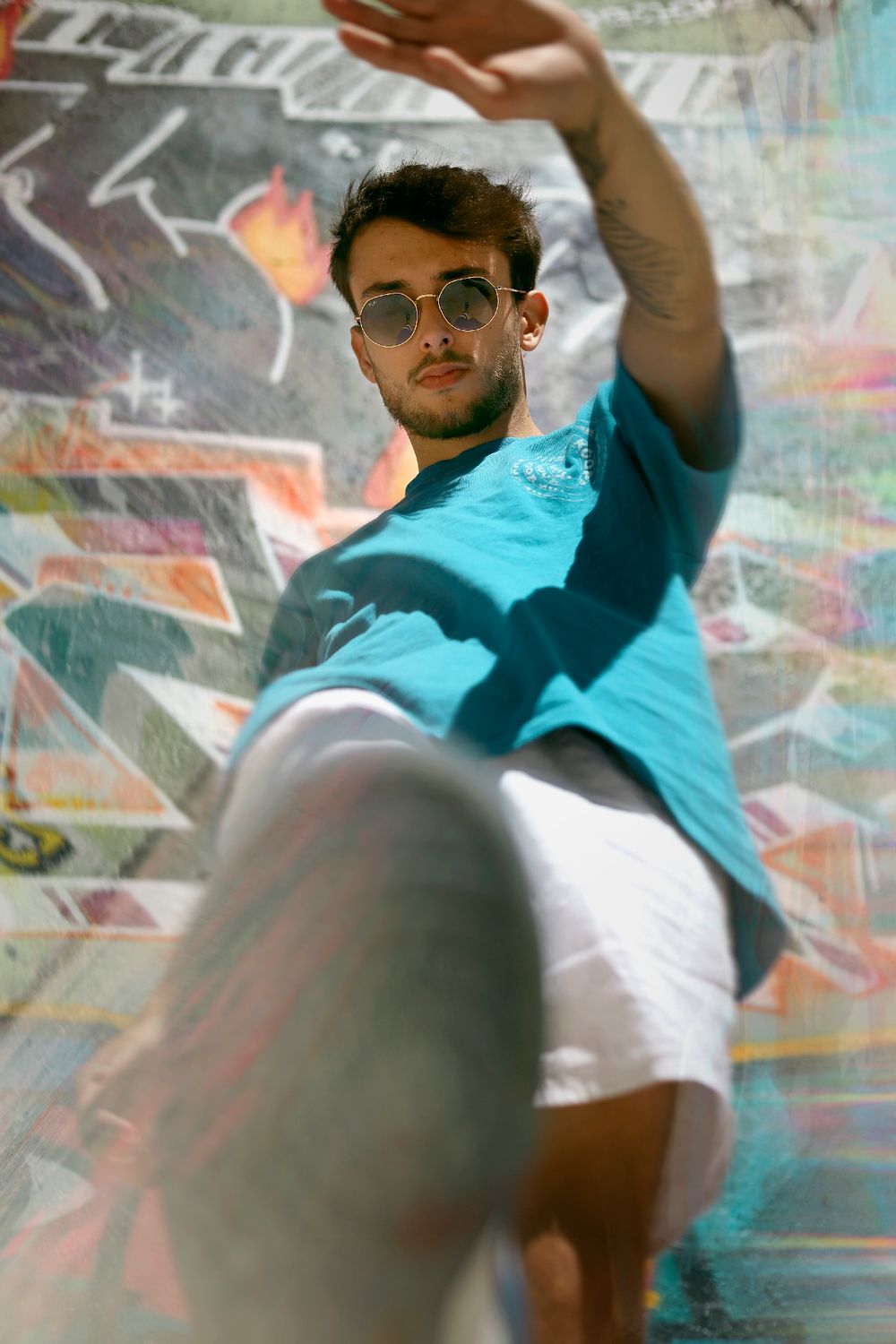 Photographie de Chaemi Studio, photographe à Montpellier. Portrait d'un homme vêtu d'un t-shirt bleu devant un mur de graffitis