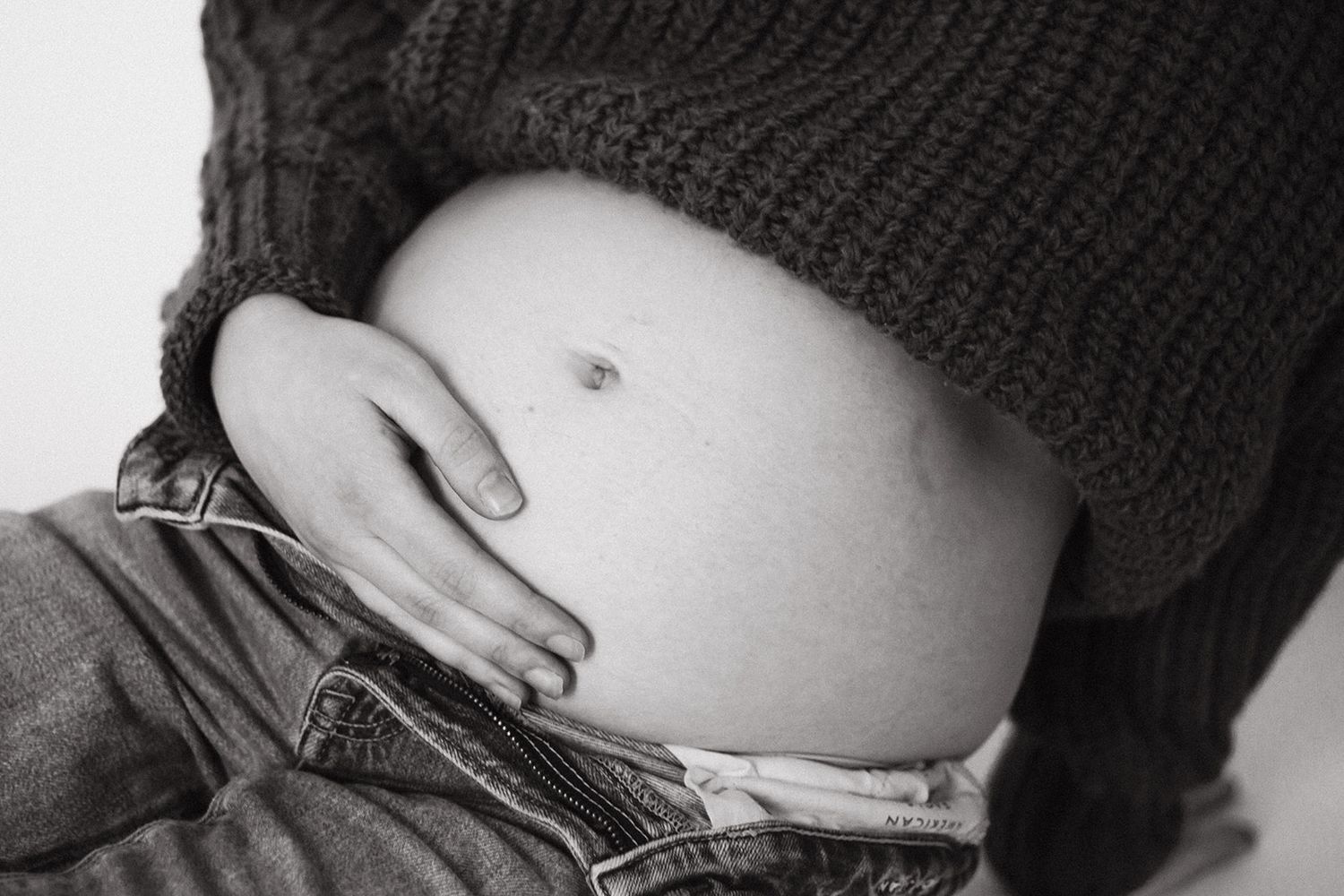 Close up of mama holding pregnant belly during maternity session.