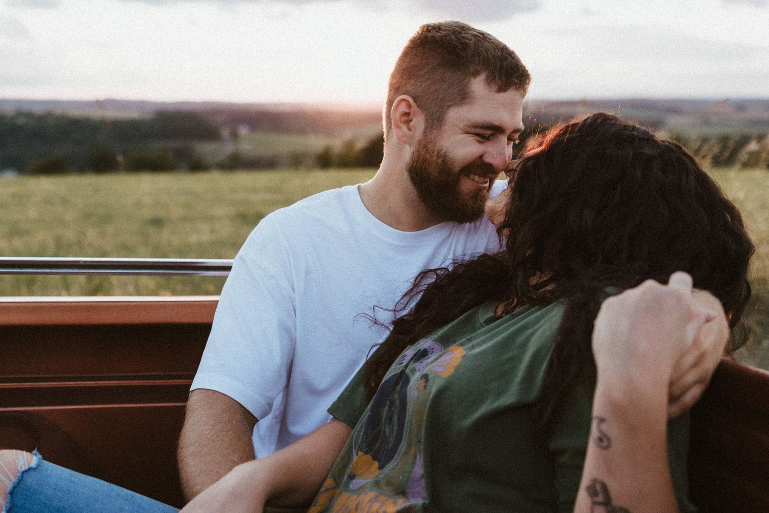 a man smiling down at a woman while holding her hand in the bed of a truck