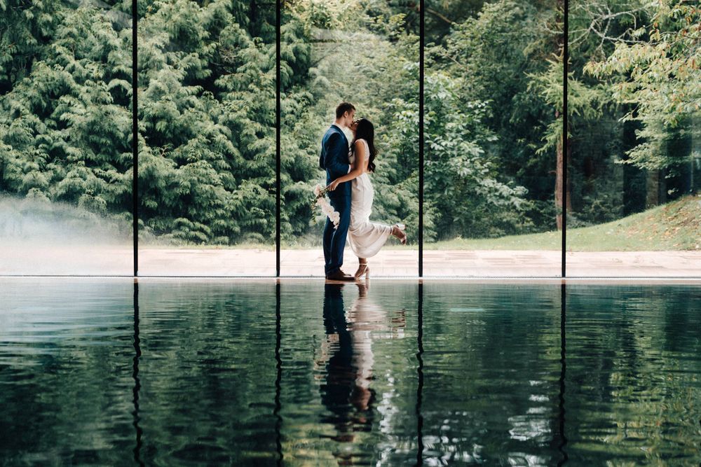 Bride and groom kissing at the swimming pool Cowley Manor
