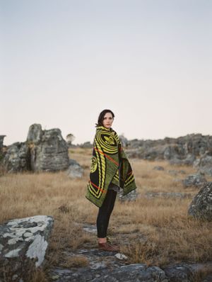 Mountainous Kaapschehoop in the background with a woman standing wrapped in a Basotho blanket.