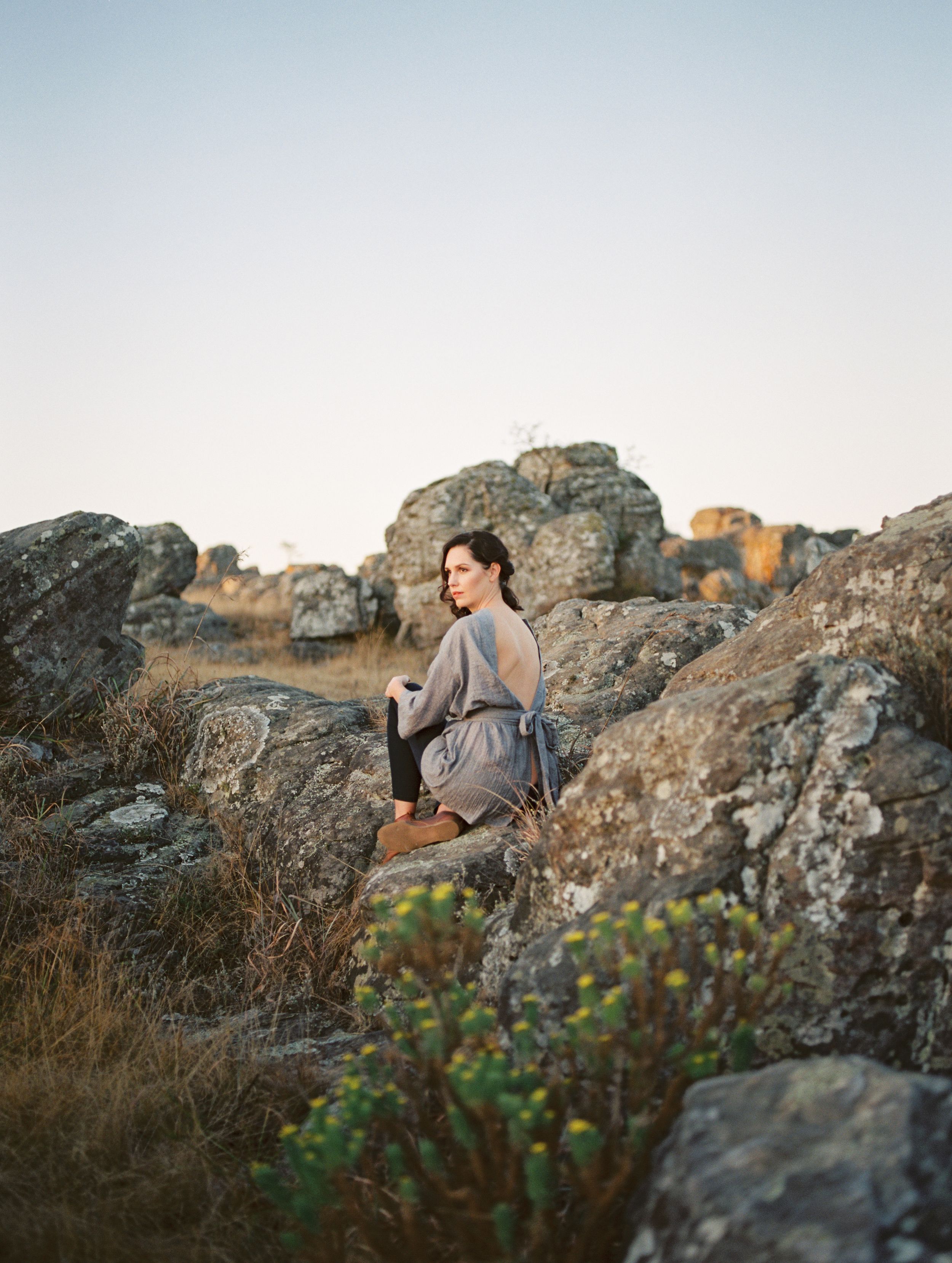 Wearing a grey Silver Swallow Design kimono Unine sits on the rocks in Kaapschehoop.