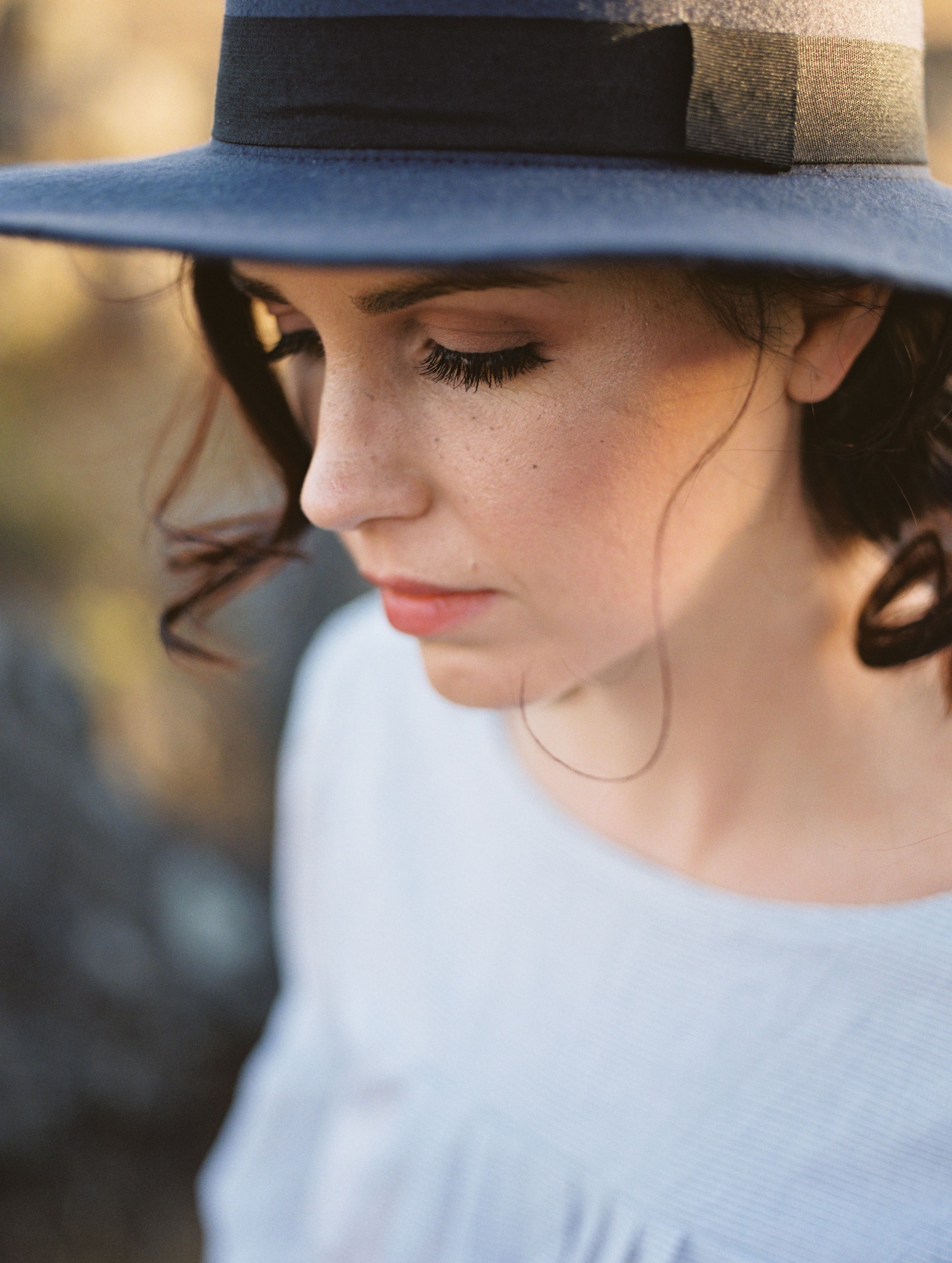 A freckled woman wearing a felt wide rim hat.